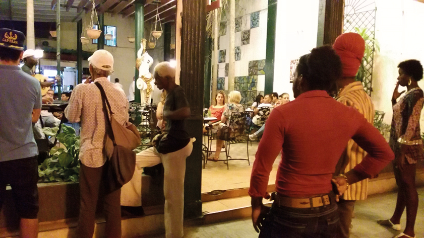Turistas en un concierto de son, mientras un grupo de cubanos presenta la actuación desde la calle. Foto / Patricio Zambrano.